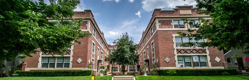 A large red brick building with a tree in front.