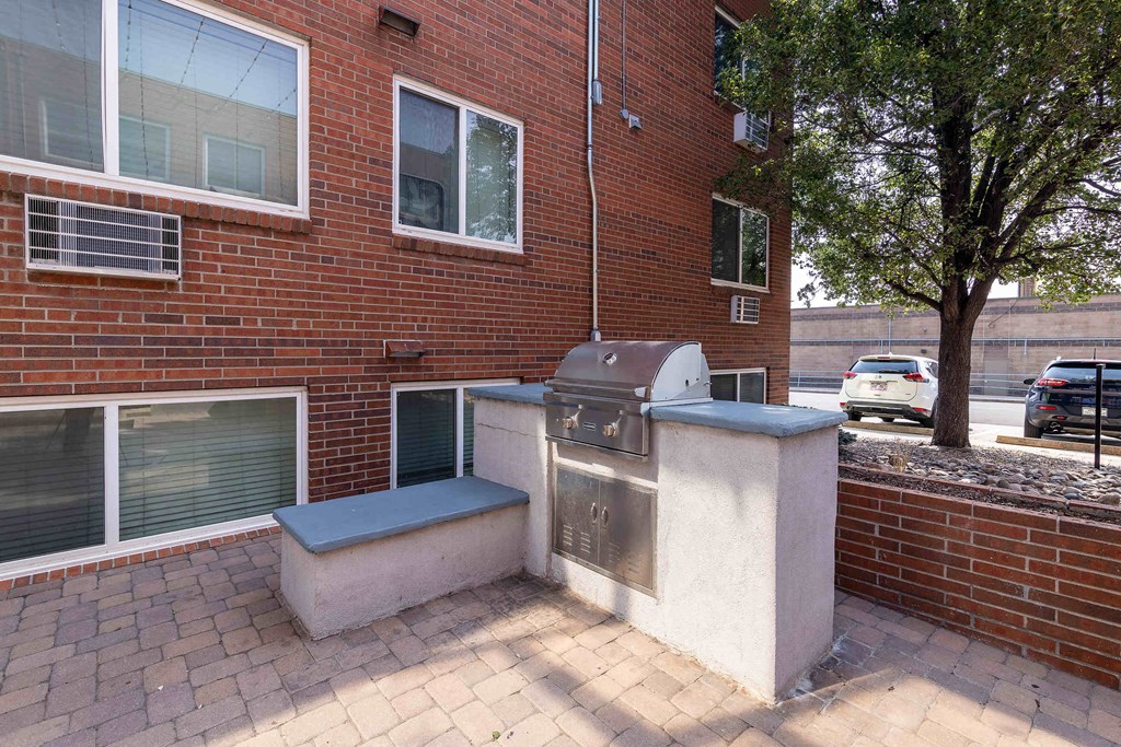 a brick building with a grill and a tree in front of it
