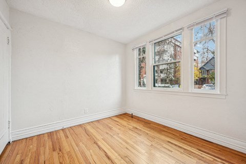 A room with wooden floors and white walls with a window.