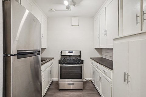 A kitchen with white cabinets and a stainless steel refrigerator.