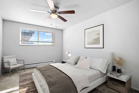 A bedroom with a bed, chair, and a ceiling fan.