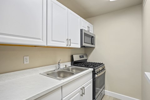 A kitchen with white cabinets and a stove top oven.