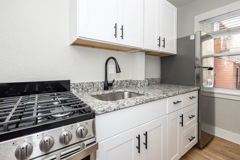 A kitchen with a black stove top oven and white cabinets.