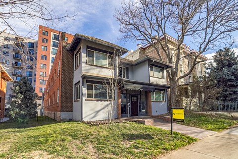 A two-story house with a yellow sign in front.