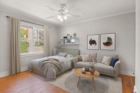 A bedroom with a bed and a couch with a ceiling fan.