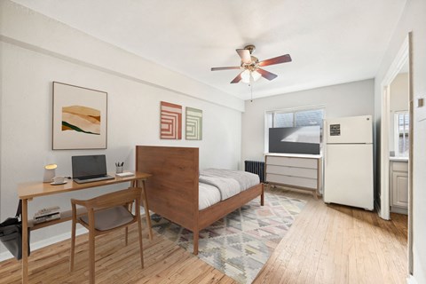 a bedroom with a bed and a desk and a ceiling fan