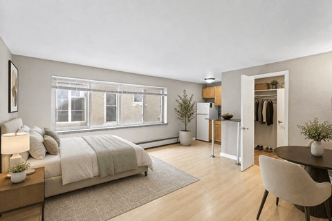A bedroom with a bed, a desk, a chair, and a potted plant.