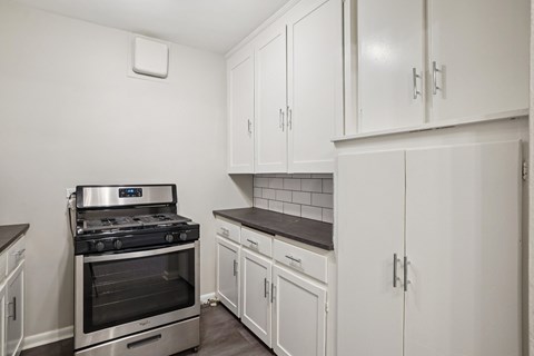 A kitchen with white cabinets and a stove top oven.