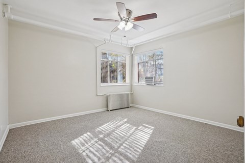 A room with a ceiling fan and a window with blinds.