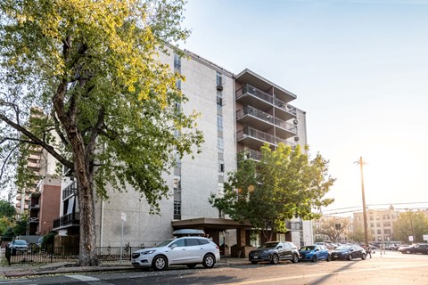 A silver car is parked on the side of the street in front of a building.