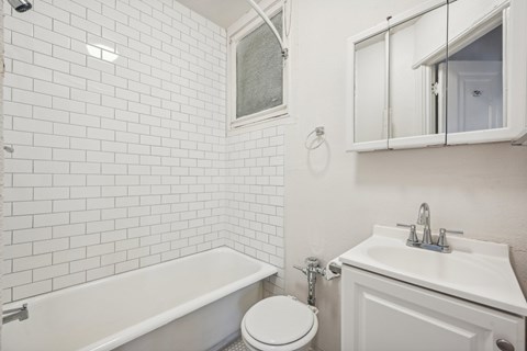 A white bathroom with a toilet, sink, and bathtub.