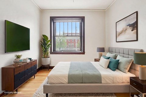 A bedroom with a large bed and a window overlooking a red building.
