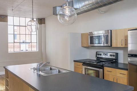 A kitchen with a stove, sink, and cabinets.