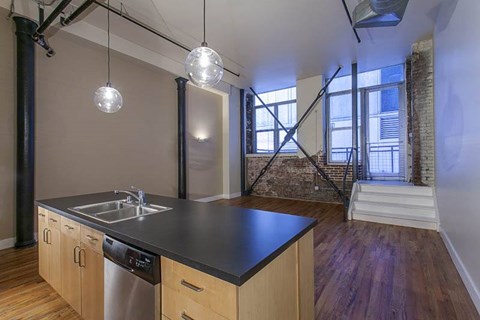 A kitchen with wooden floors and a brick wall in the background.