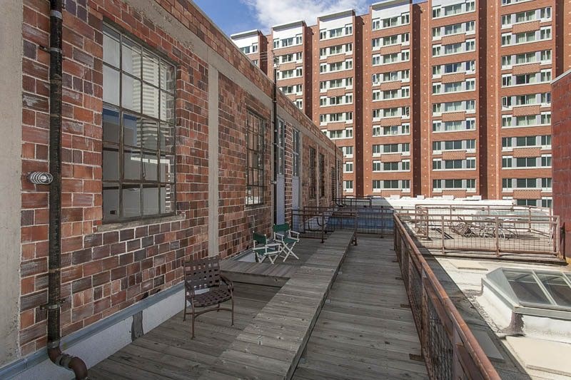 A balcony with a table and chairs overlooks a courtyard.