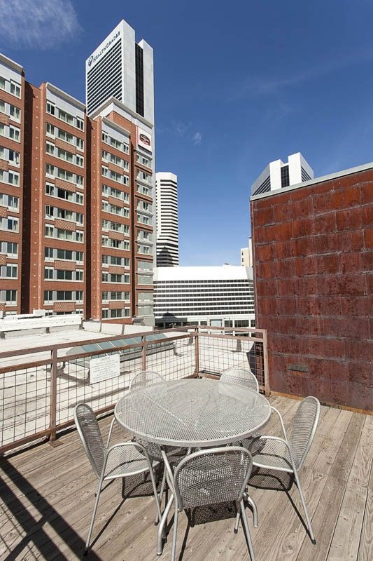 A table and chairs on a balcony with a city skyline in the background.