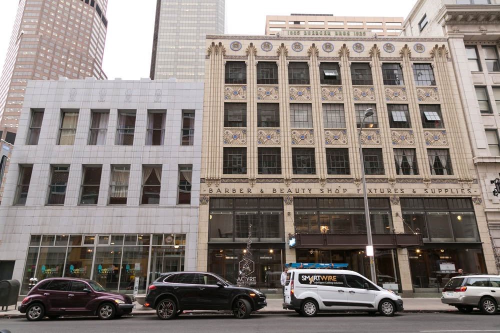 A city street with a building that has a sign for a barber and beauty shop.