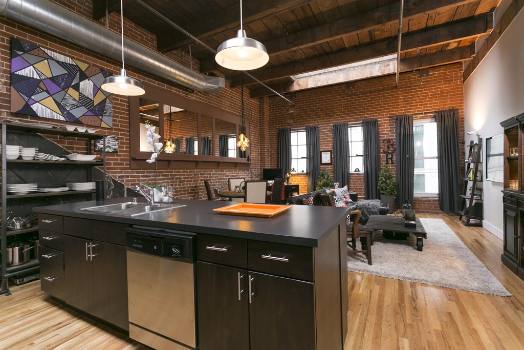 A kitchen with black cabinets and a wooden floor.