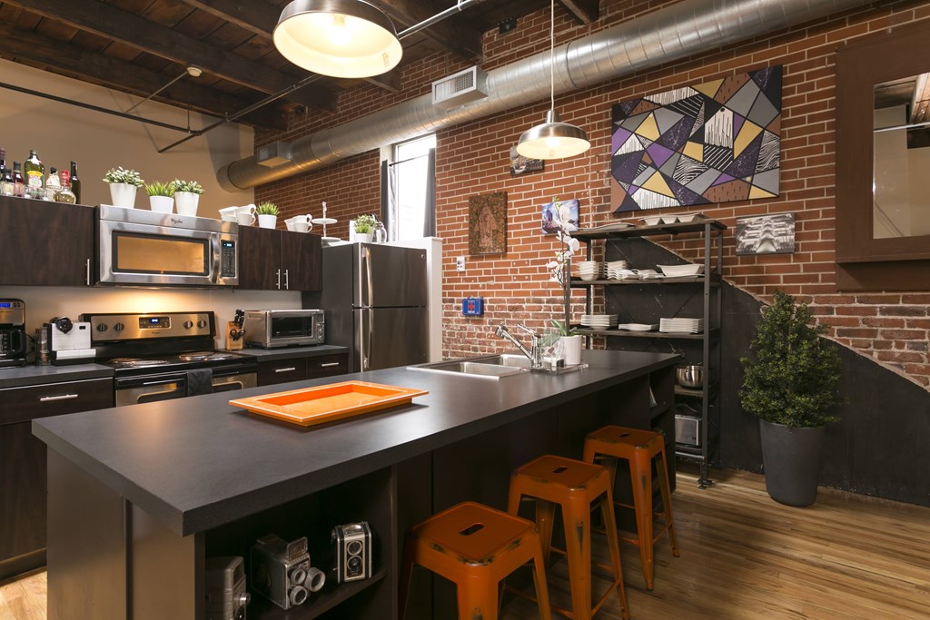 A kitchen with a black countertop and wooden floors.