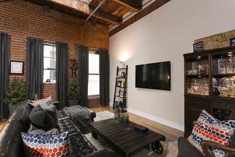 A living room with a black couch and a wooden coffee table.