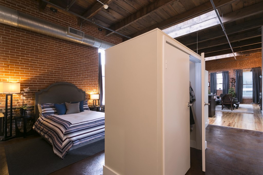 A bedroom with a bed and a large white wardrobe.