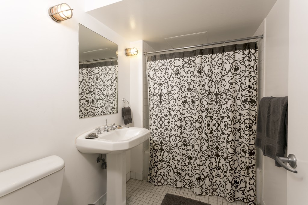 A bathroom with a white sink and a black and white shower curtain.