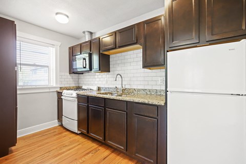 a kitchen with dark wood cabinets and white appliances