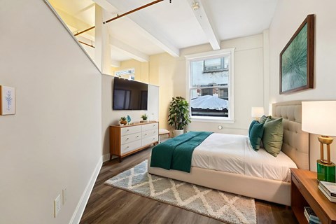A bedroom with a bed, nightstand, and a window.