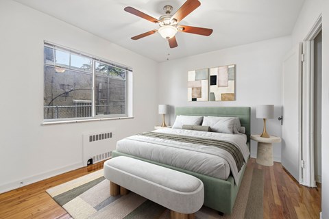 A bedroom with a bed, a lamp, and a ceiling fan.