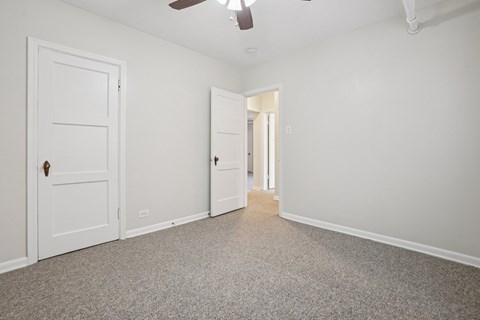 A room with a white door and a white ceiling fan.