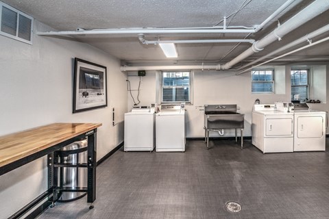 A laundry room with a washer and dryer on the wall and a table with a bench.