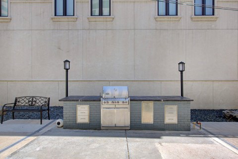 A small grey building with a white door and windows is situated in front of a building with windows.
