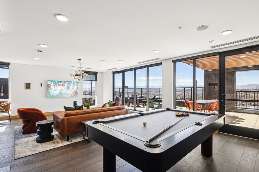 A pool table is in the middle of a room with a view of the ocean.