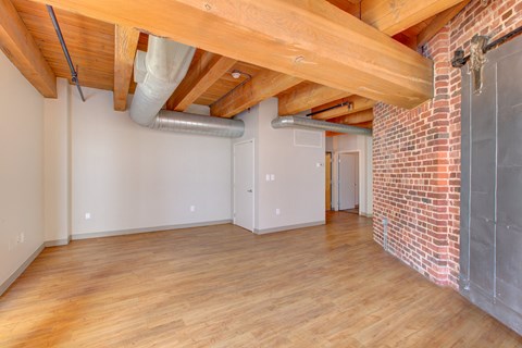 a living room with a brick wall and wood floors and a ceiling with exposed beams