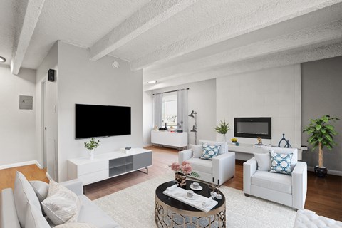 a living room with white furniture and a tv on the wall