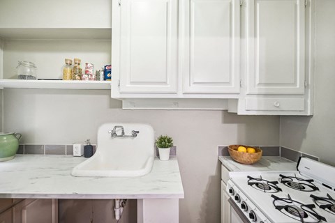a kitchen with white cabinets and a sink and a stove