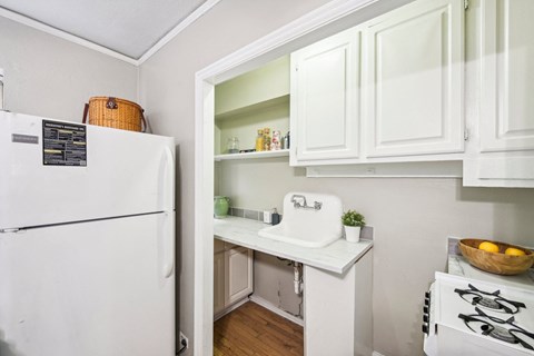 a small kitchen with white cabinets and a sink and a refrigerator