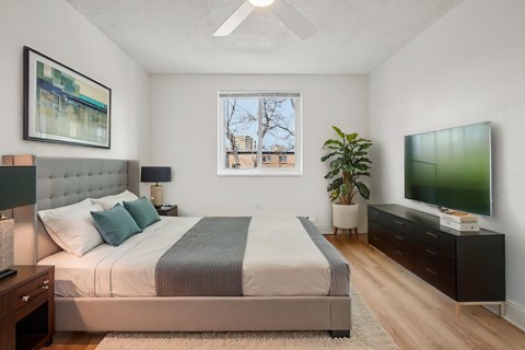 A bedroom with a large bed, a television, and a window with a view of a building outside.
