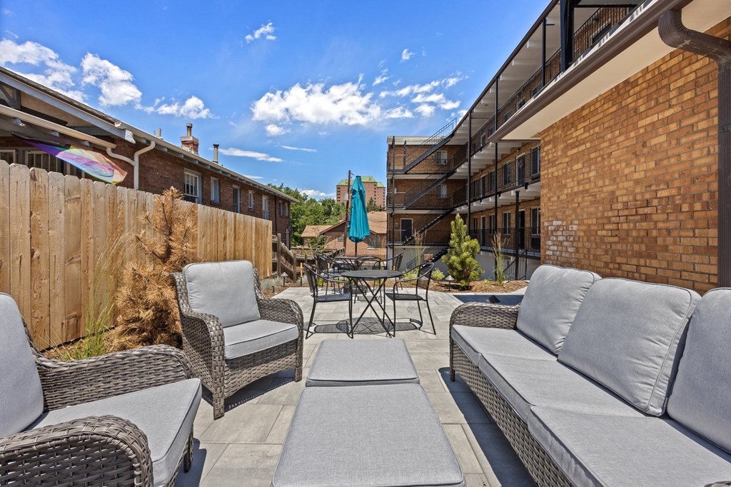 A patio with grey couches and a table with chairs.