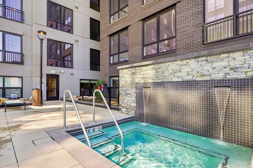 A small pool with a metal fence is surrounded by a stone wall.