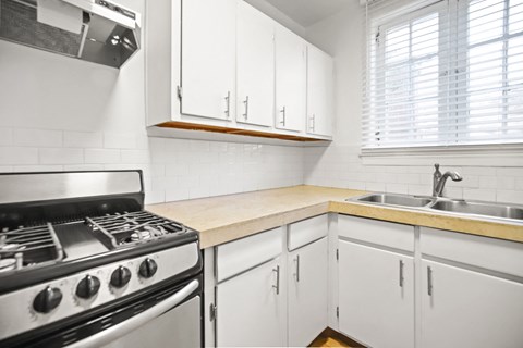 a kitchen with white cabinets and a stove and sink