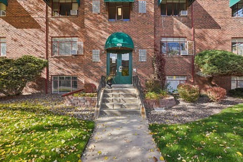 A red brick building with a green door and steps leading up to it.