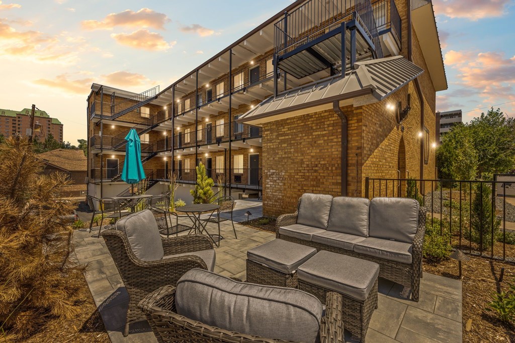 A patio with a couch, chairs, and a table with a blue umbrella.