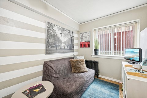 a small living room with a gray couch and a window