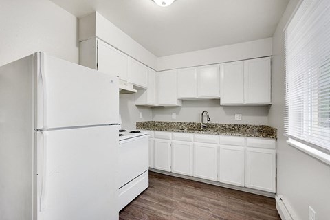 A white kitchen with a granite countertop and white cabinets.