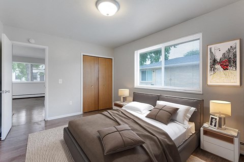 A bedroom with a bed, nightstand, and a painting on the wall.