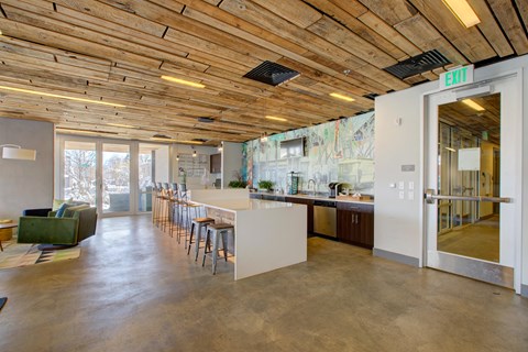 a room with a kitchen and a bar with chairs