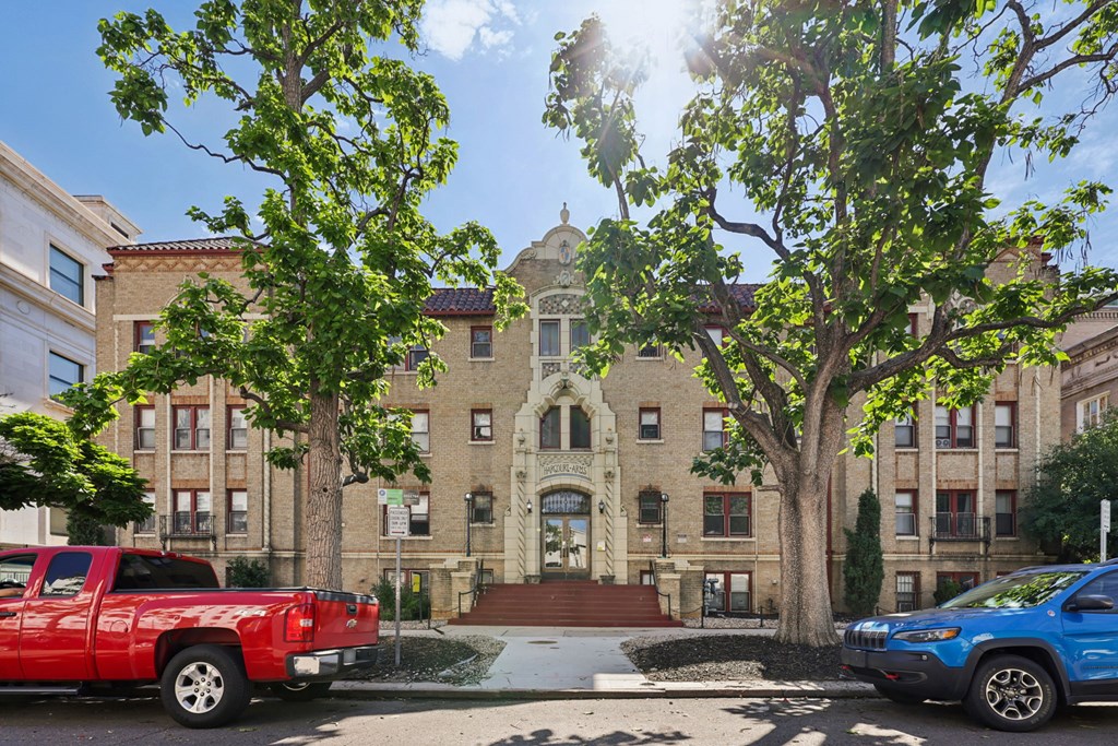 A red truck is parked on the left side of a street, and a blue car is parked on the right side.