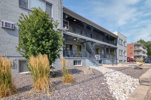 a building with a porch and a tree in front of it