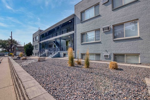 an apartment building with a gravel yard in front of it